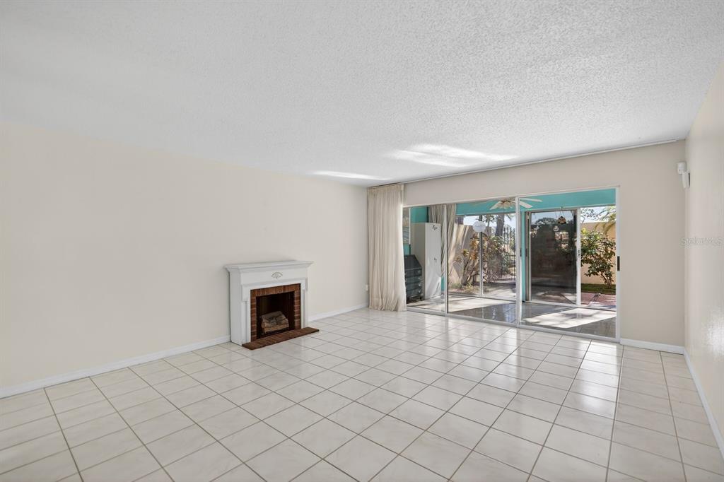 A living room with white tile floors, a fireplace, and sliding glass doors to a patio — 1111 W FAITH CIRCLE UNIT 1003, BRADENTON, FL