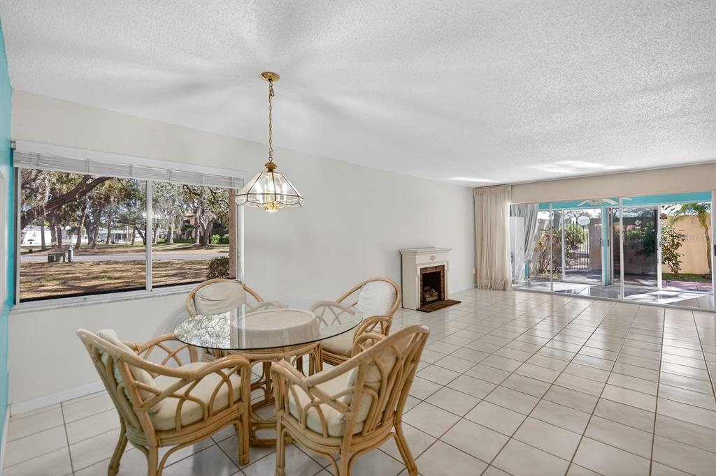 A dining area with a glass table and rattan chairs sits beside a tiled living space — 1111 W FAITH CIRCLE UNIT 1003, BRADENTON, FL