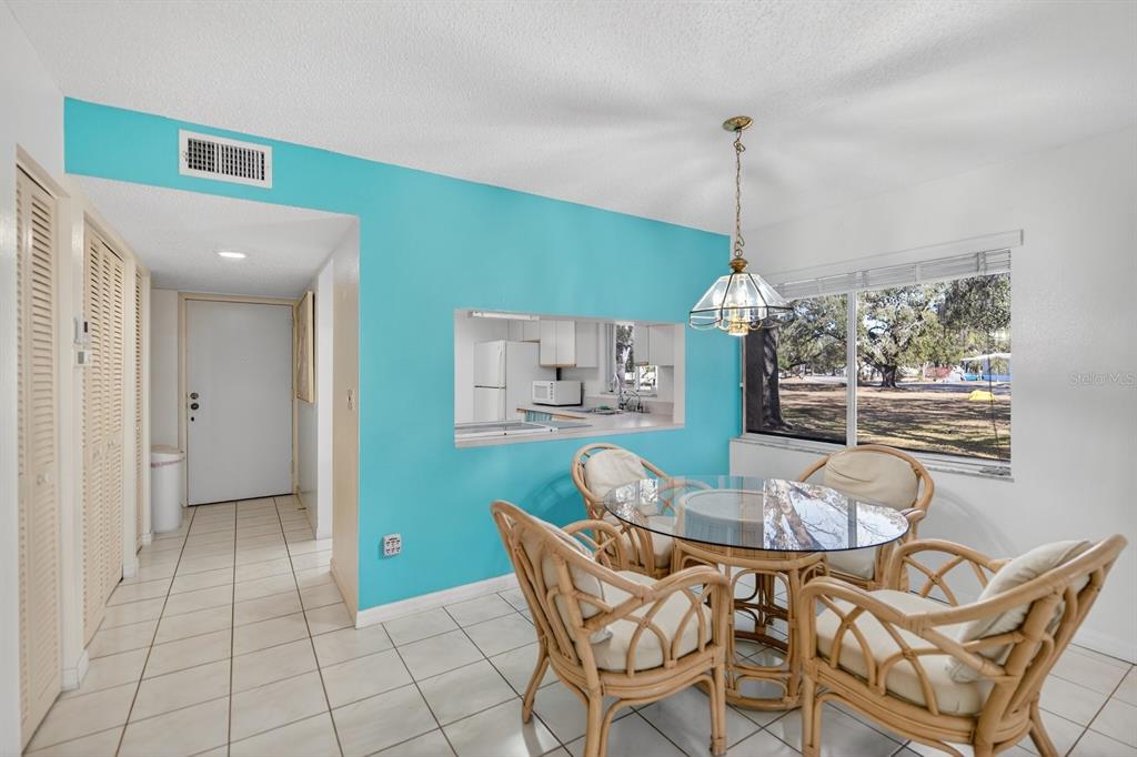 A dining area features a glass-topped rattan table, a turquoise accent wall, and tiled floors — 1111 W FAITH CIRCLE UNIT 1003, BRADENTON, FL