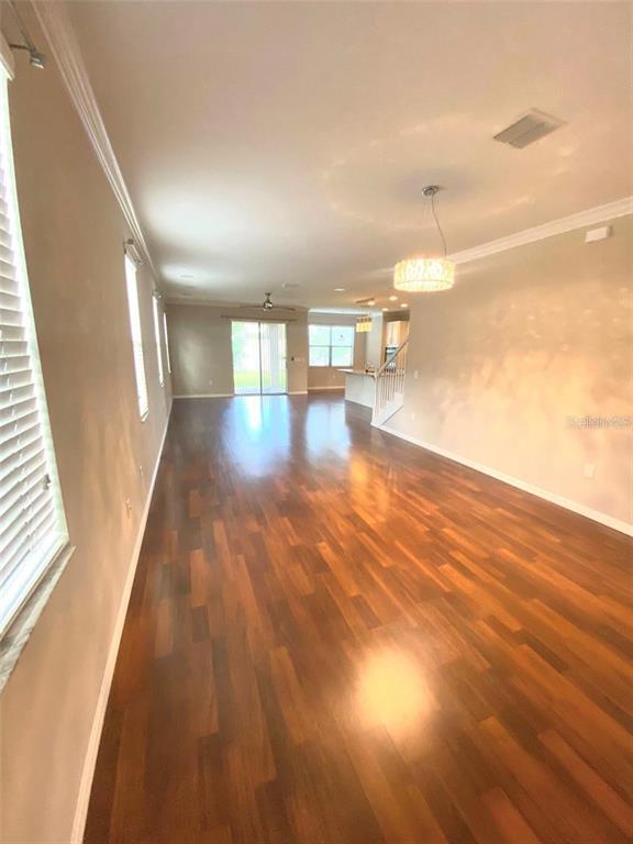 An open-concept living area features hardwood floors, a modern chandelier, and a kitchen in back — 10007 LEYBURN COURT, ORLANDO, FL