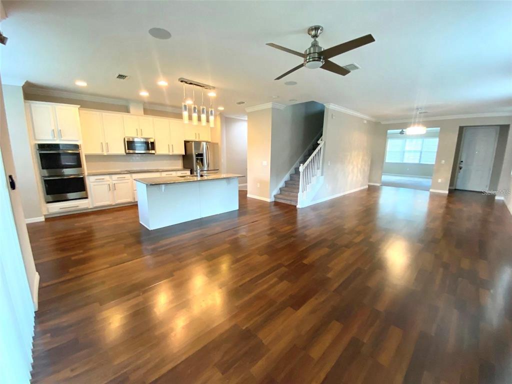 An open-concept kitchen with white cabinetry and a center island overlooks a spacious living area — 10007 LEYBURN COURT, ORLANDO, FL