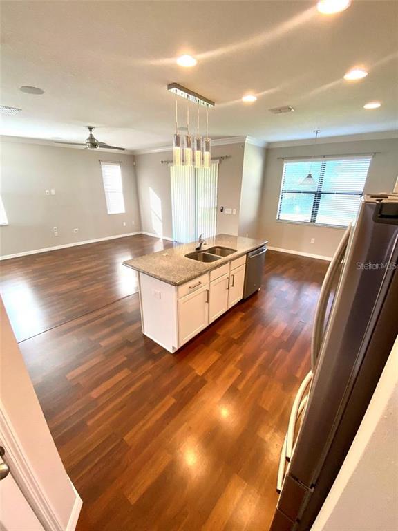 A kitchen island with a granite countertop sits in an open-concept room with wood flooring — 10007 LEYBURN COURT, ORLANDO, FL