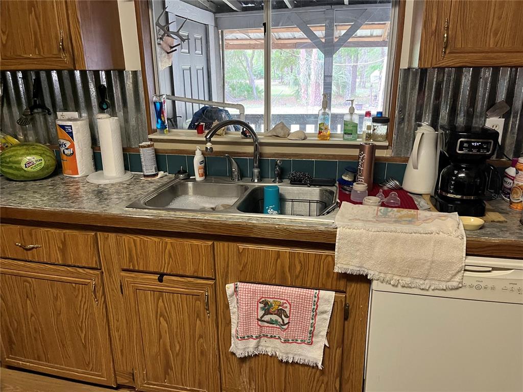 A kitchen features wood cabinets, a double-basin sink, a window, and a corrugated metal backsplash — 12501 SW HIGHWAY 200, DUNNELLON, FL
