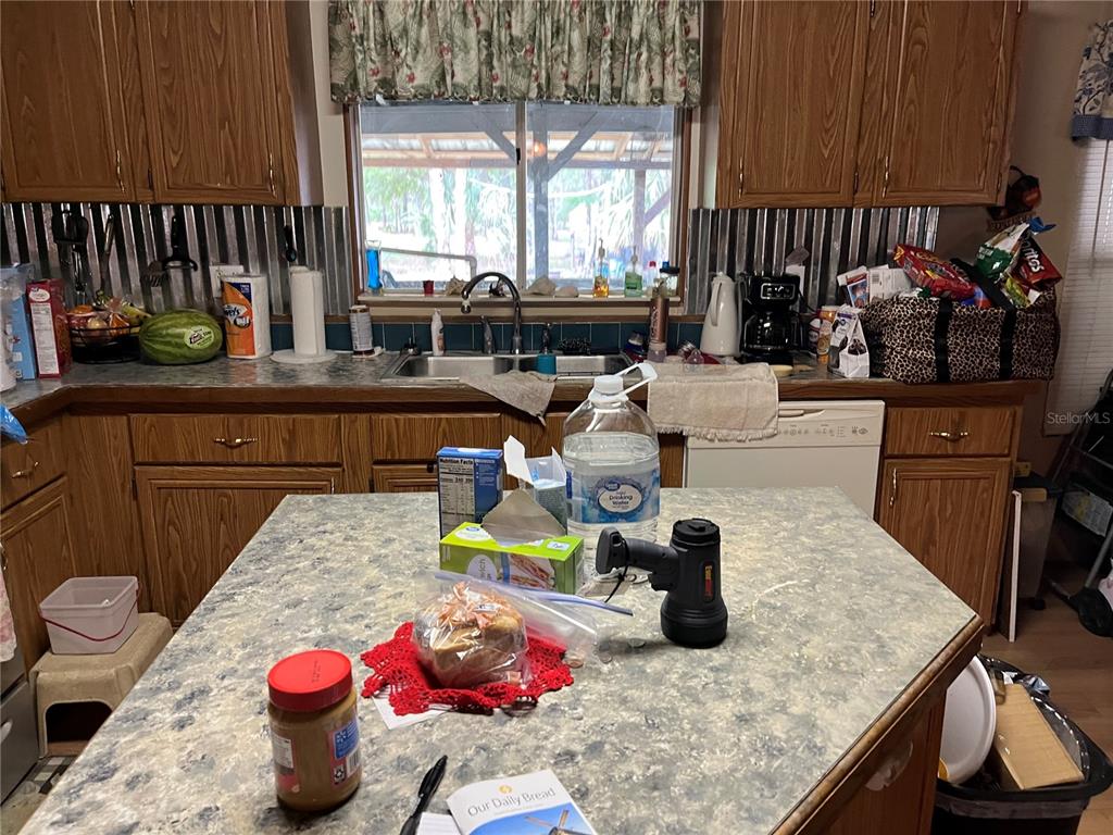 A kitchen with wood cabinets, a metal backsplash, and a central island with countertop items — 12501 SW HIGHWAY 200, DUNNELLON, FL
