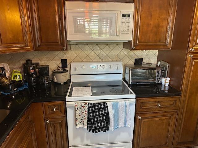 A kitchen features dark wood cabinets, black countertops, a white stove, and a microwave — 7600 NW 5th Place # 106, Margate FL 33063, MARGATE, FL