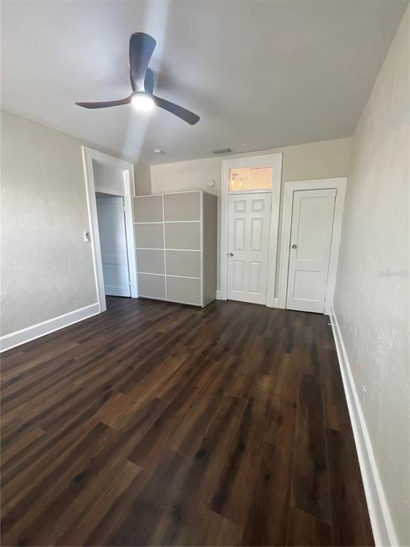 A room with dark wood-look flooring, a ceiling fan, and three white doors — 2608 CENTRAL AVENUE UNIT 4, ST PETERSBURG, FL