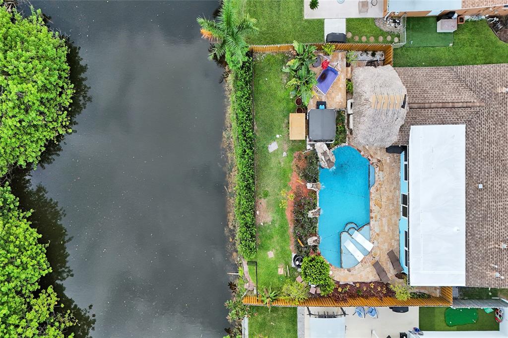 An aerial view shows a backyard with a swimming pool, tiki hut, and canal access — 12341 NW 29TH MANOR, SUNRISE, FL