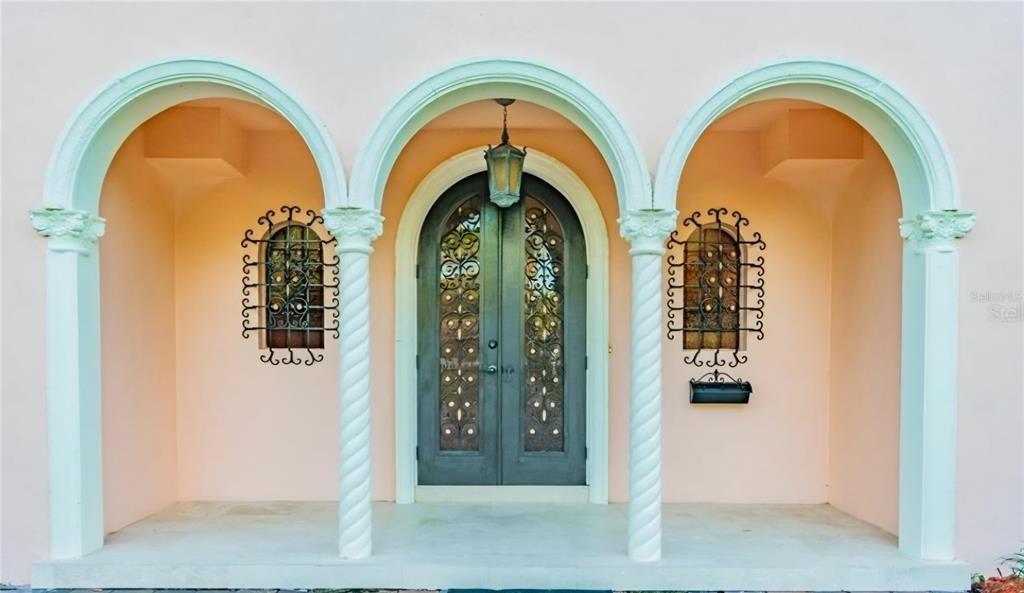 An arched entryway features a double door with decorative metalwork flanked by two matching windows — 411 72ND STREET S, ST PETERSBURG, FL