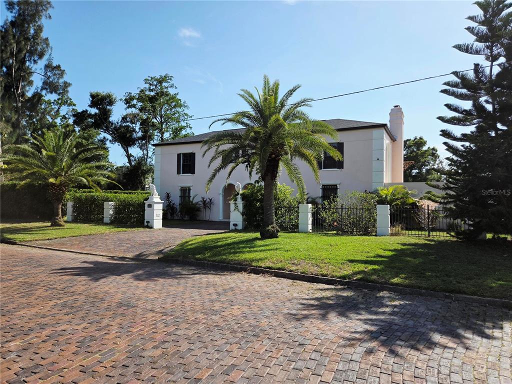 A two-story stucco house with a brick driveway and palm trees in the front yard — 411 72ND STREET S, ST PETERSBURG, FL