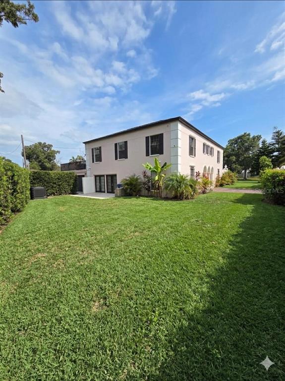 A two-story, light-colored house with a large green lawn and landscaping — 411 72ND STREET S, ST PETERSBURG, FL