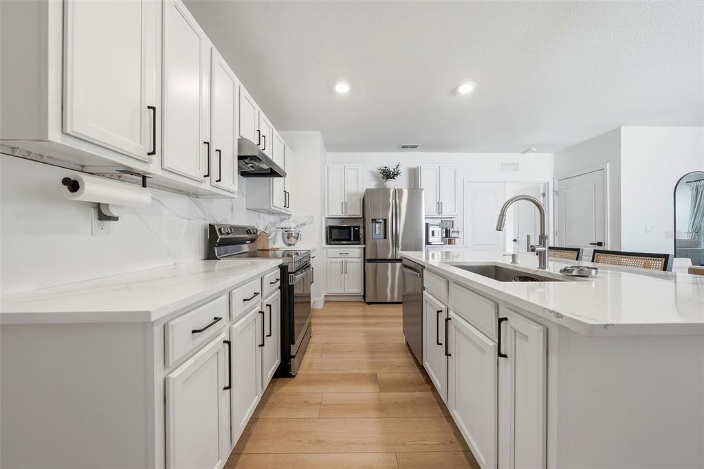 A modern kitchen features white cabinets, stainless steel appliances, and a central island with seating — 30309 ARMENIA ROAD, LEESBURG, FL