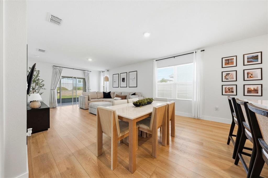 A bright, open-concept living and dining area features light wood flooring and neutral furniture — 30309 ARMENIA ROAD, LEESBURG, FL