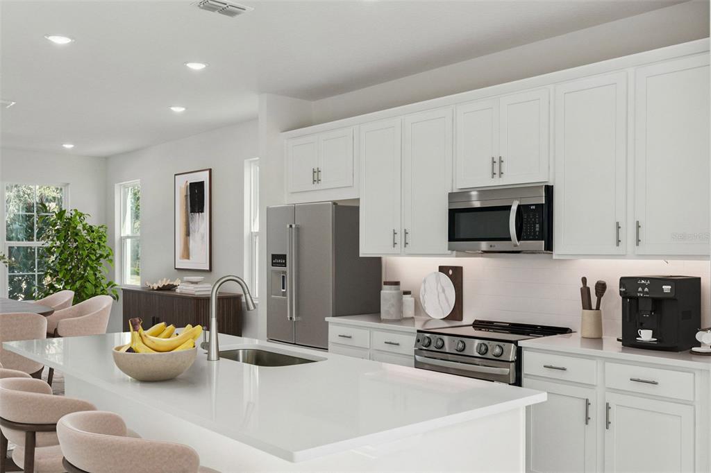 A modern open-concept living room features a grey sectional sofa, wooden coffee table, and kitchen — 2369 HUANIER COURT, APOPKA, FL