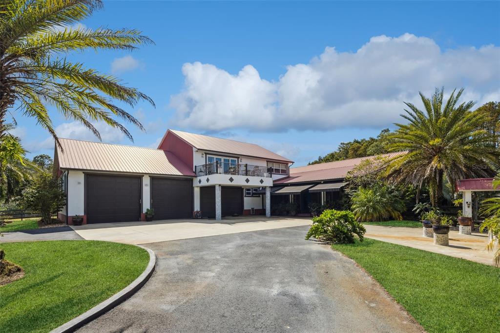 A two-story house with a metal roof, multiple garage doors, and a second-story balcony — 8515 BAY LAKE ROAD, GROVELAND, FL