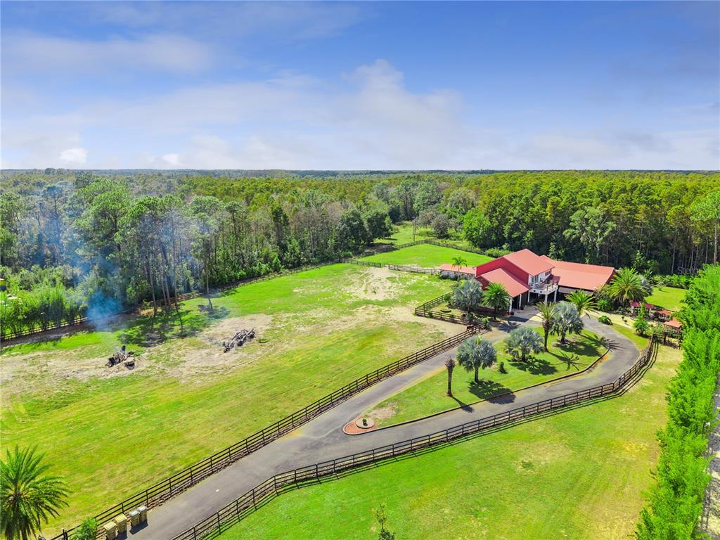 An aerial view shows a house with a red roof, a circular driveway, and fenced pastures — 8515 BAY LAKE ROAD, GROVELAND, FL