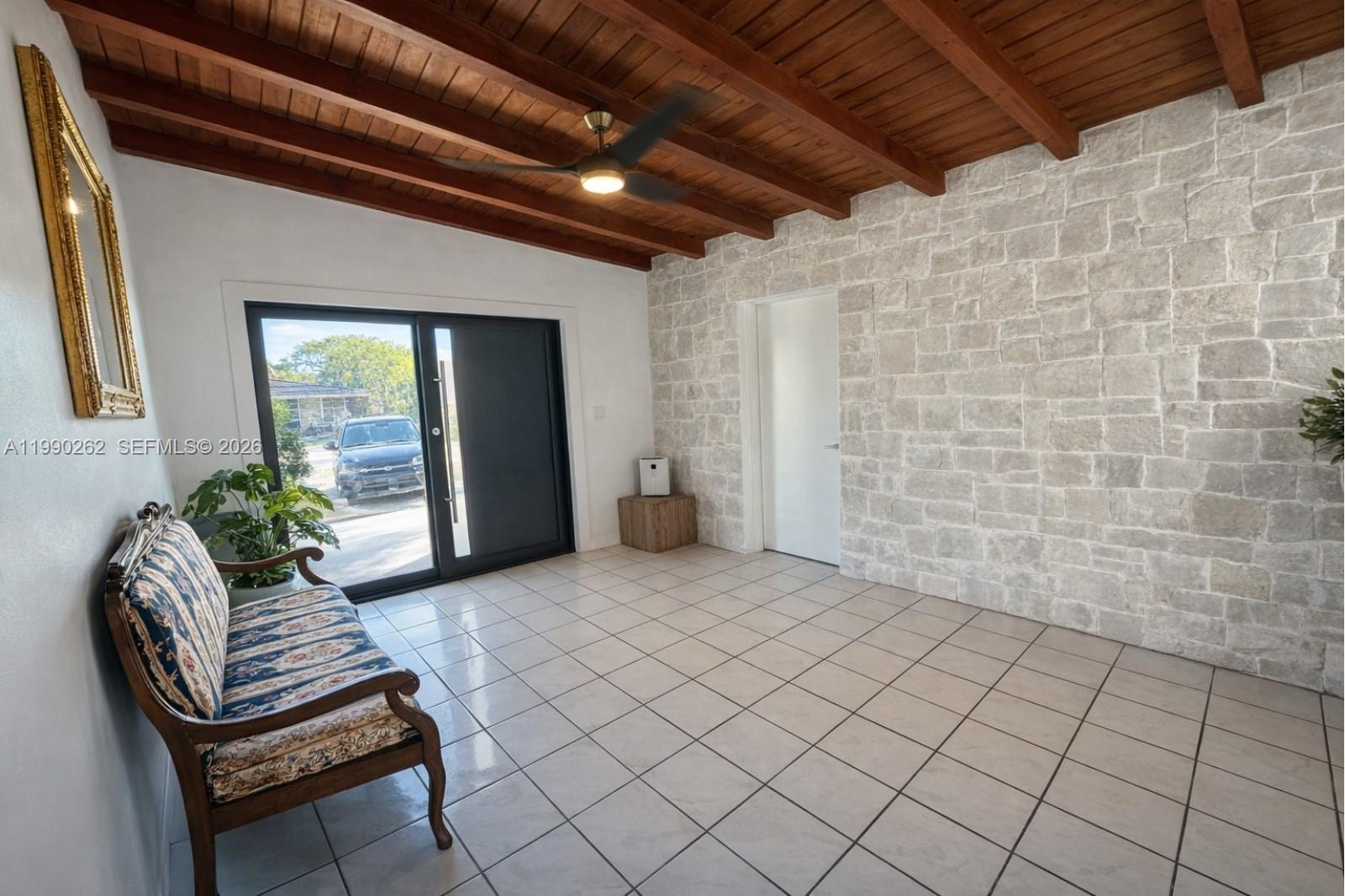 An entryway features a stone accent wall, wood-beamed ceiling, tile flooring, and a glass door — 6561 SW 34th St, Miami FL 33155, MIAMI, FL