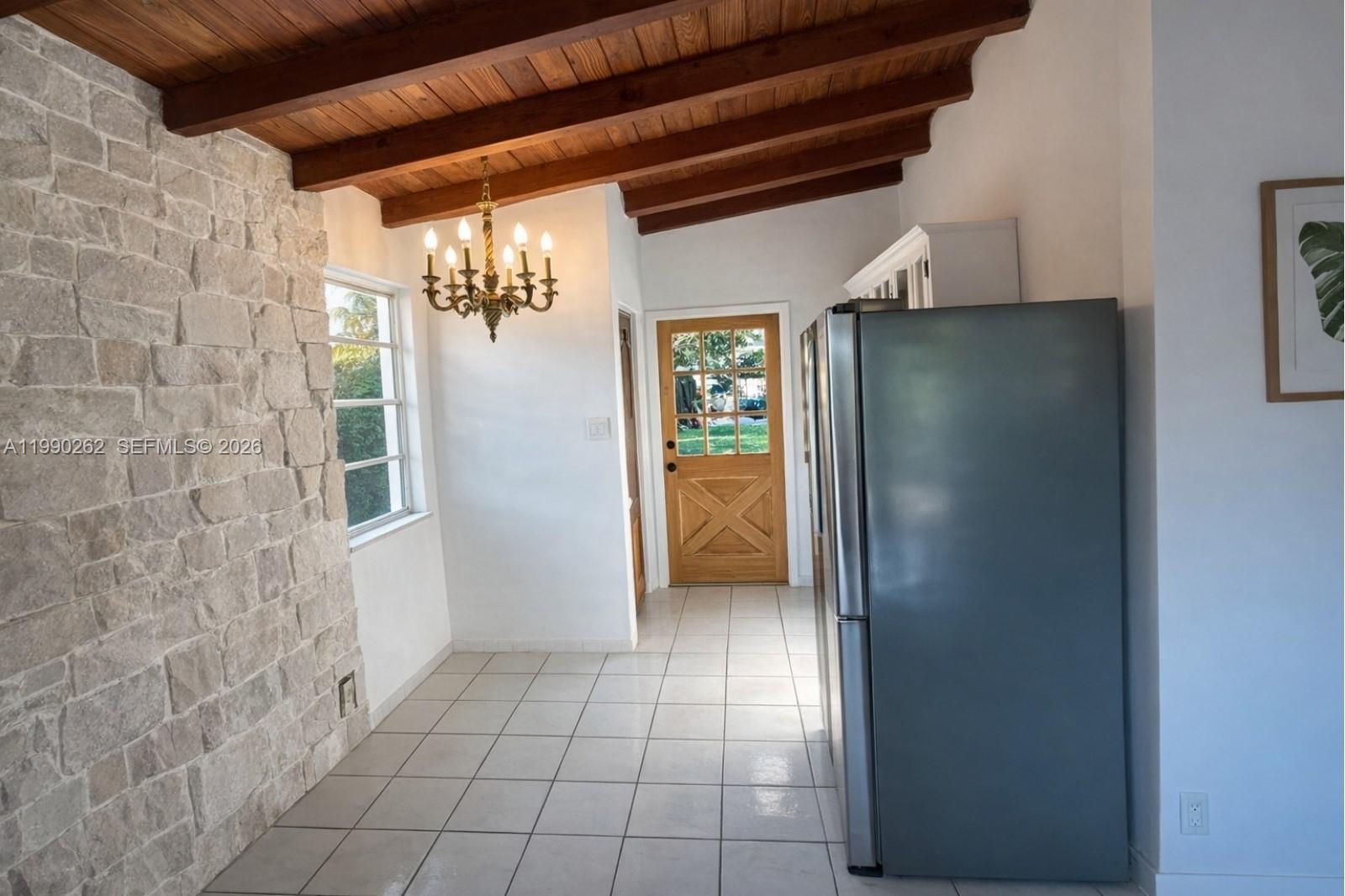 A kitchen area features a stone wall, wood-beamed ceiling, tile flooring, and a wooden door — 6561 SW 34th St, Miami FL 33155, MIAMI, FL