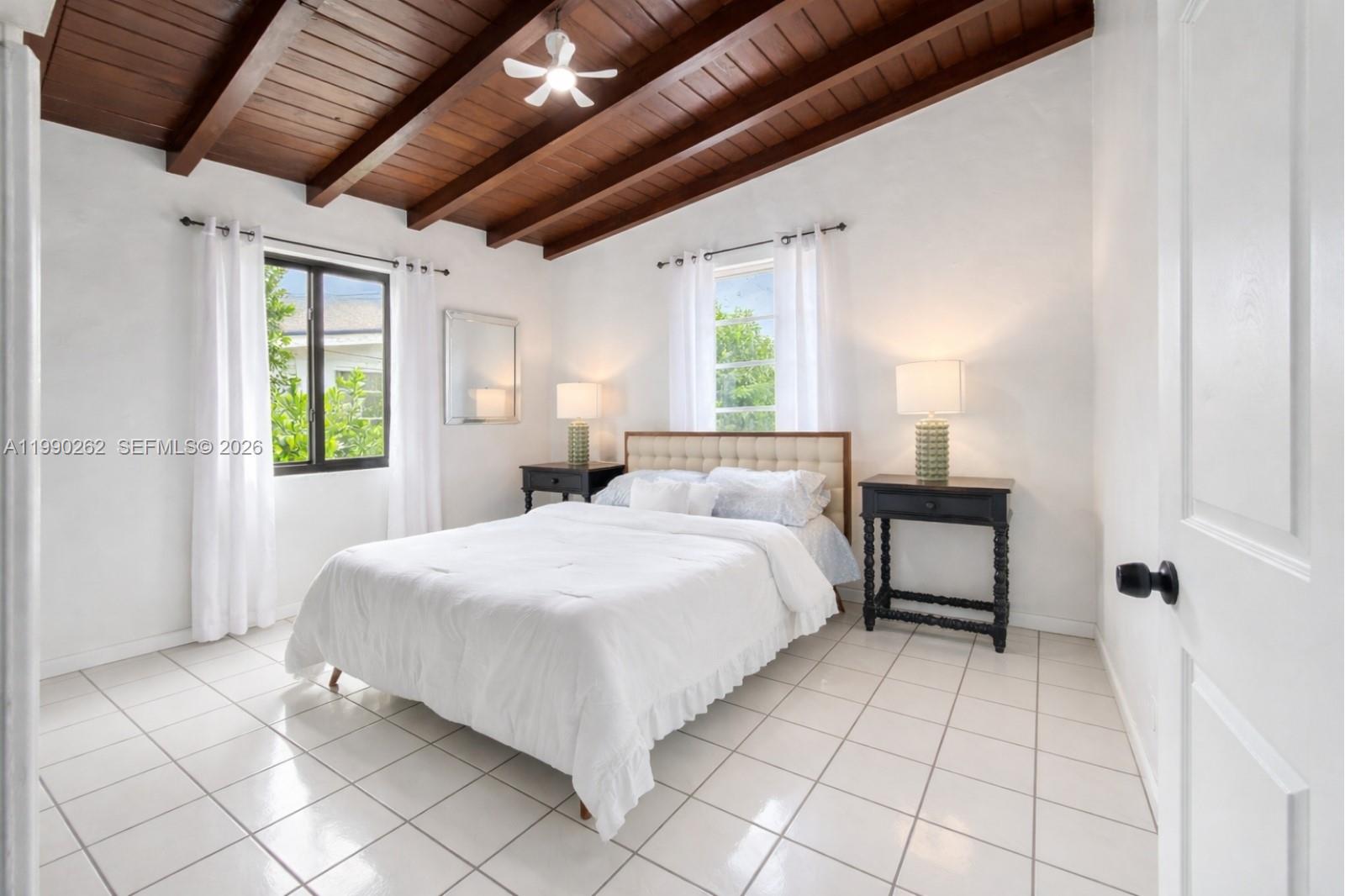 A bedroom features white tile floors, a wood-beamed ceiling, and a bed with white bedding — 6561 SW 34th St, Miami FL 33155, MIAMI, FL