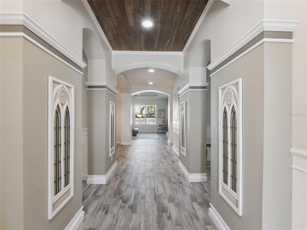 A hallway features wood-look tile flooring, a wood-paneled ceiling, and decorative arched wall insets — 1025 SADIE RIDGE ROAD, CLERMONT, FL