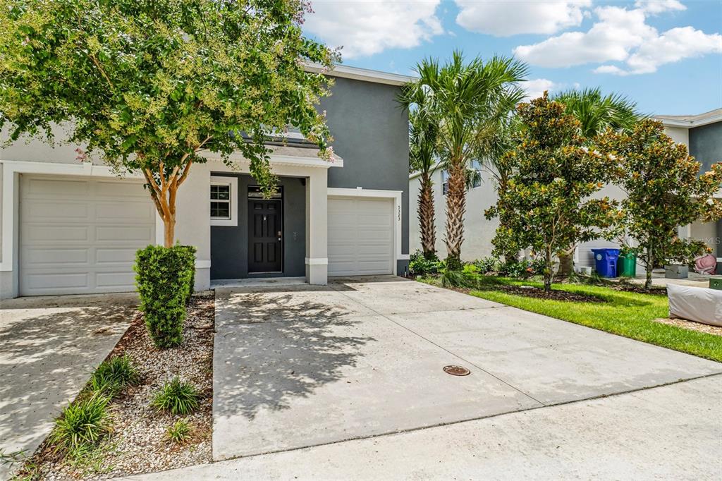 A two-story gray house with a two-car garage, front door, and landscaped yard — 5323 LOBLOLLY LANE, WILDWOOD, FL