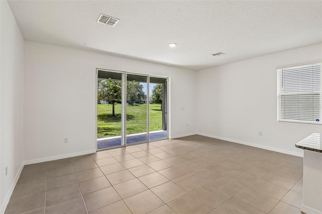A bright room features light tile flooring, white walls, sliding glass doors, and a window — 5323 LOBLOLLY LANE, WILDWOOD, FL