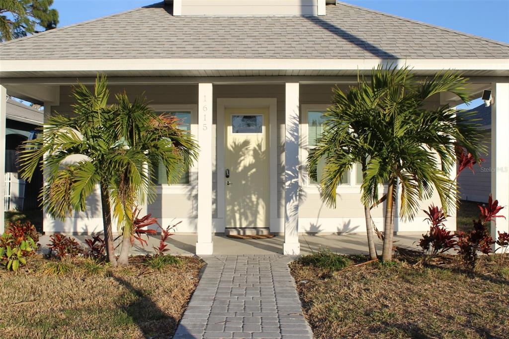 A front view of a single-story house with a paved walkway and two palm trees — 1615 17TH STREET W, BRADENTON, FL
