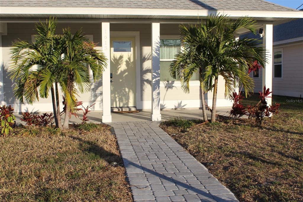 A paved walkway leads to the front porch of a house with light-colored siding — 1615 17TH STREET W, BRADENTON, FL