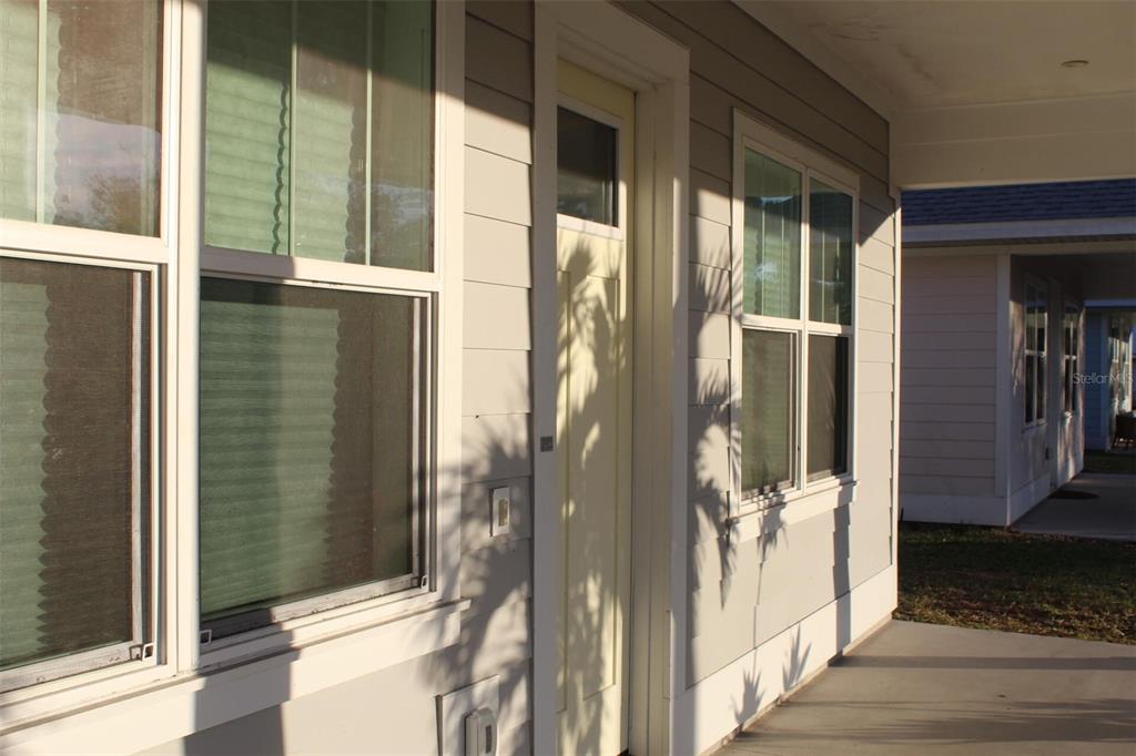A light-colored front door sits on a covered porch next to windows with blinds — 1615 17TH STREET W, BRADENTON, FL