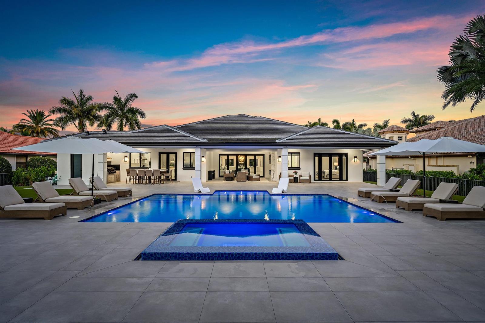 A backyard patio features a swimming pool, a raised spa, and lounge chairs at sunset — 6087 Wildcat Run, West Palm Beach FL 33412, WEST PALM BEACH, FL