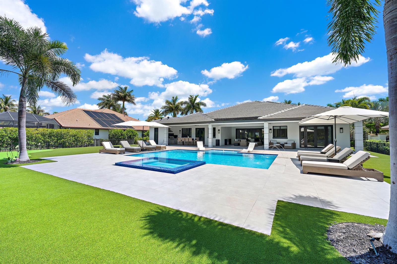 A backyard features a swimming pool, a spa, lounge chairs, and a covered patio area — 6087 Wildcat Run, West Palm Beach FL 33412, WEST PALM BEACH, FL