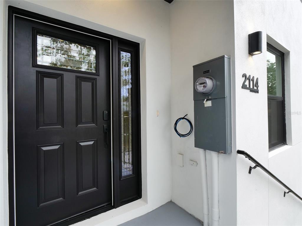 A black front door with a side window stands next to an exterior electrical meter — 2114 4TH STREET S UNIT 7, ST PETERSBURG, FL