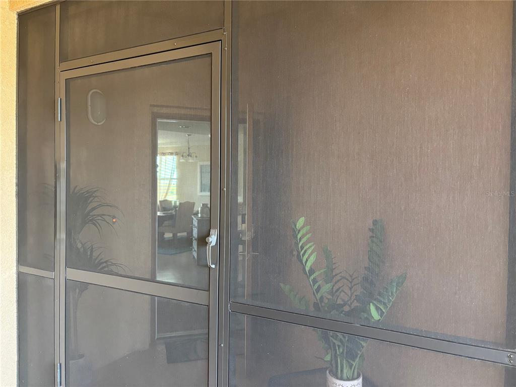 A screen door leads into a home interior with a dining area visible inside — 6509 GRAND ESTUARY TRAIL UNIT 208, BRADENTON, FL