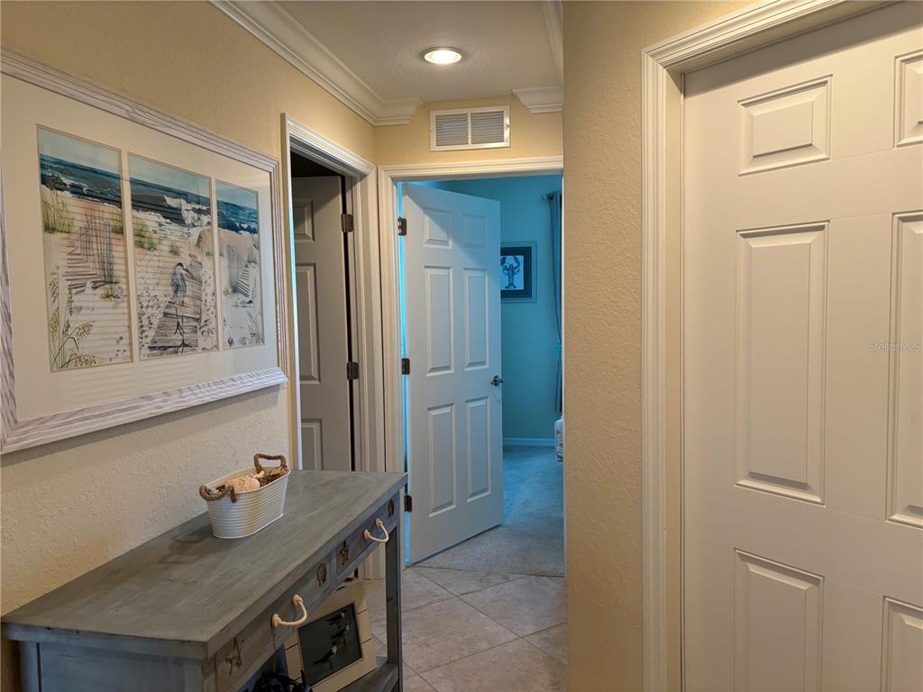 A hallway features a console table, framed beach artwork, and two open doorways — 6509 GRAND ESTUARY TRAIL UNIT 208, BRADENTON, FL