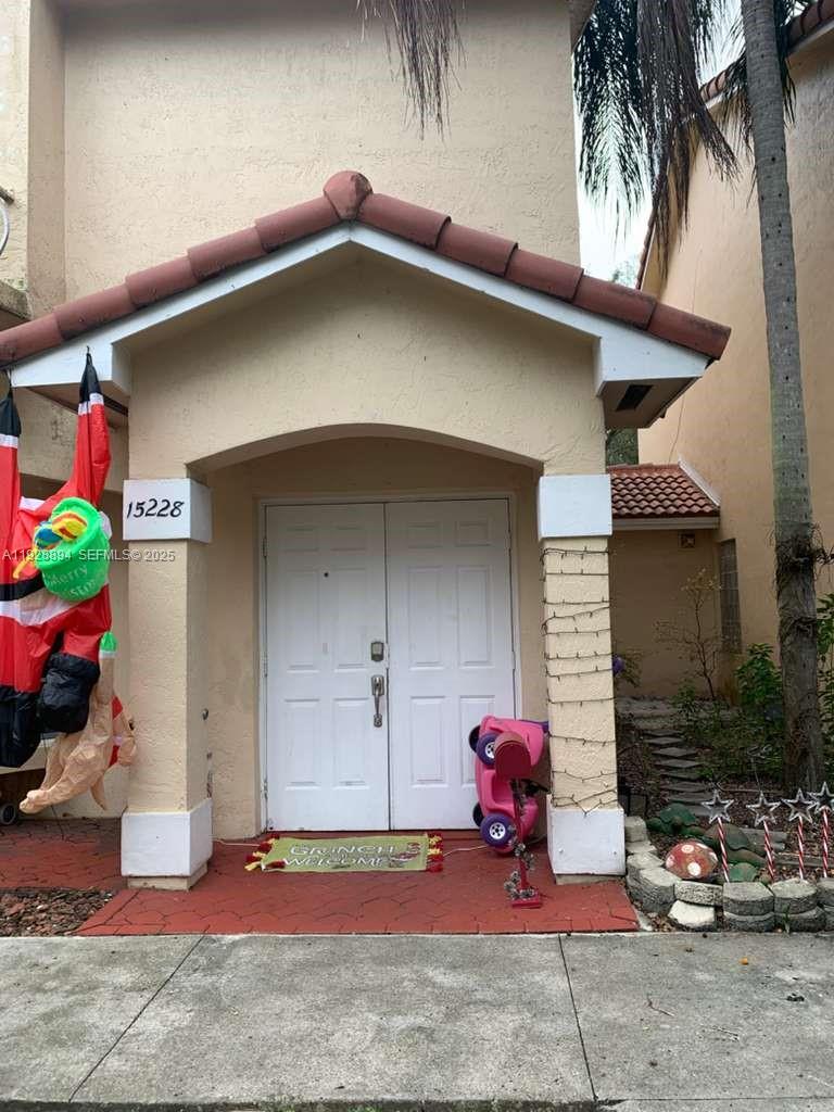 The exterior of a house features a covered entryway with double doors and holiday decorations — 15228 SW 111th St, Miami FL 33196, MIAMI, FL
