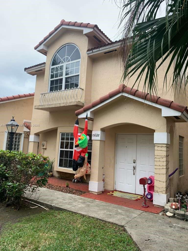 A two-story stucco house features a tiled roof, arched window, and a front porch — 15228 SW 111th St, Miami FL 33196, MIAMI, FL
