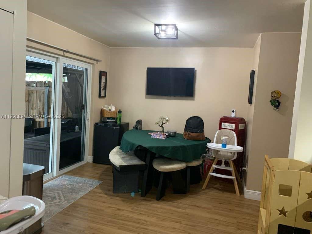 A dining area features a round table with a green cloth, wood-look flooring, and sliding doors — 15228 SW 111th St, Miami FL 33196, MIAMI, FL