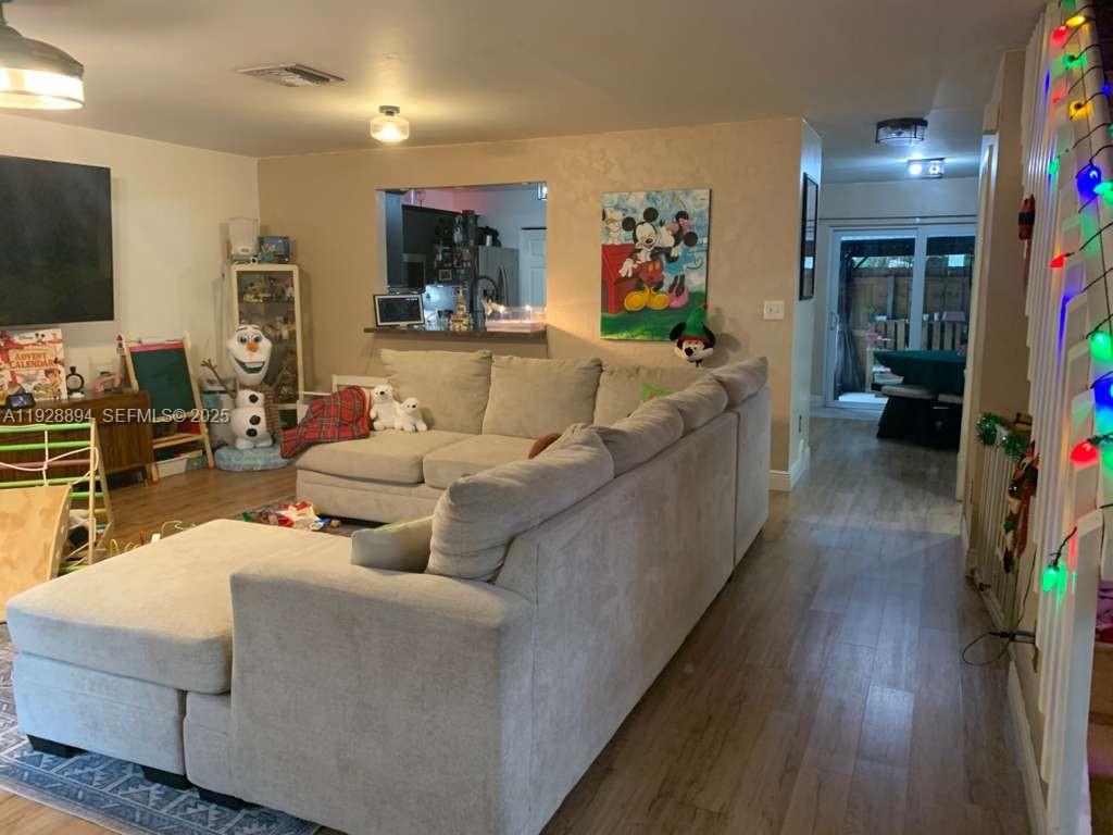 A living room features a large sectional sofa, light wood flooring, and a kitchen pass-through — 15228 SW 111th St, Miami FL 33196, MIAMI, FL