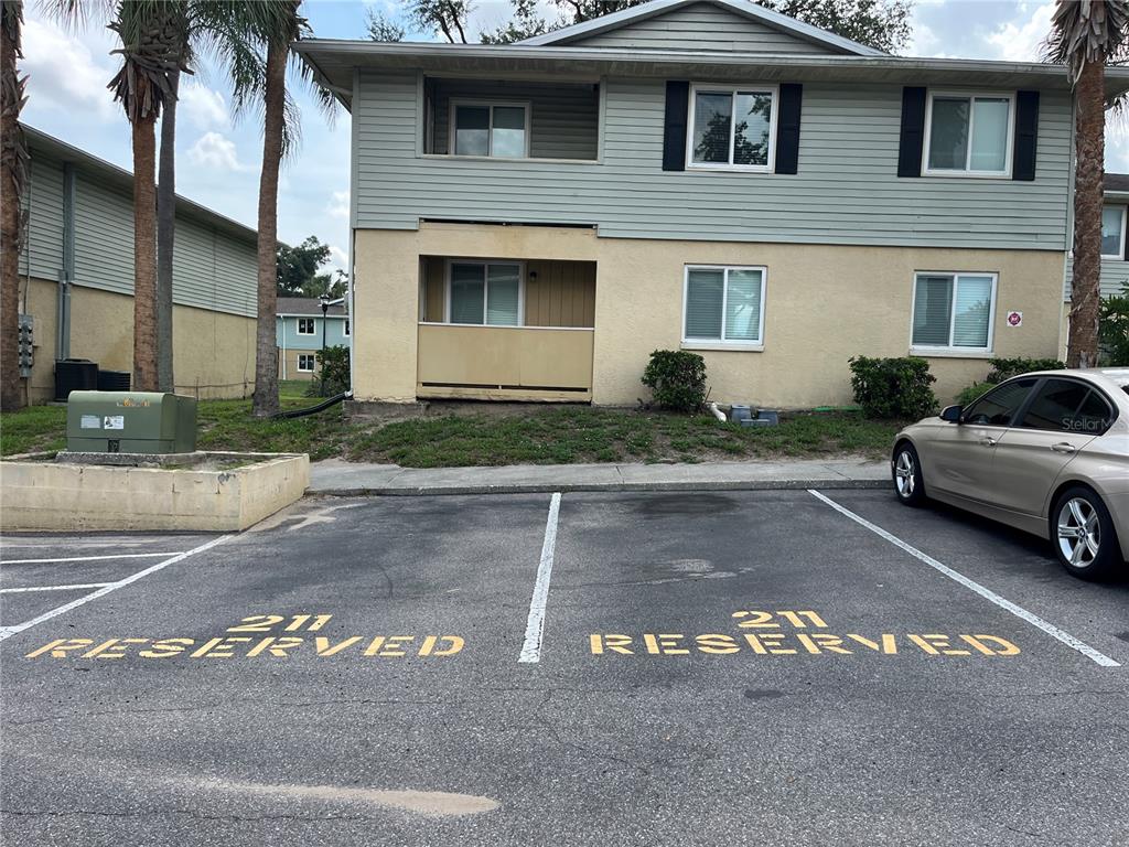 A two-story apartment building exterior features two reserved parking spaces in the foreground — 211 THORN TREE PLACE, BRANDON, FL