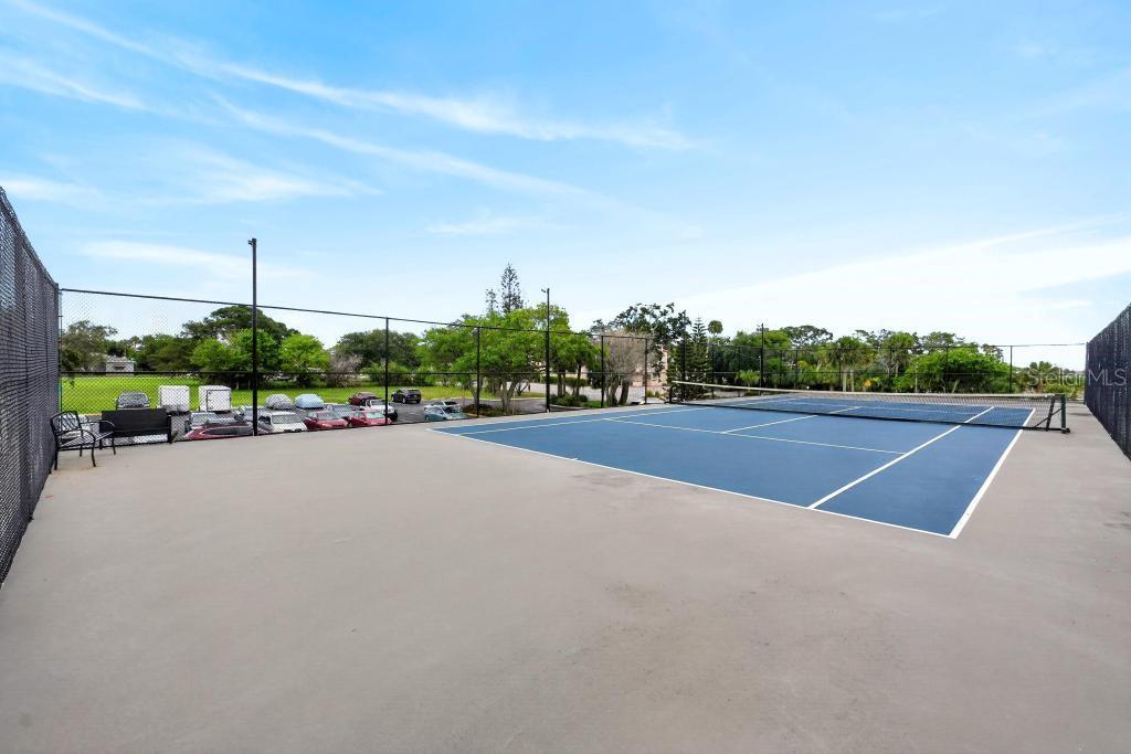 A fenced-in outdoor tennis court with a blue surface and a parking lot nearby — 925 N HALIFAX AVENUE UNIT 410, DAYTONA BEACH, FL