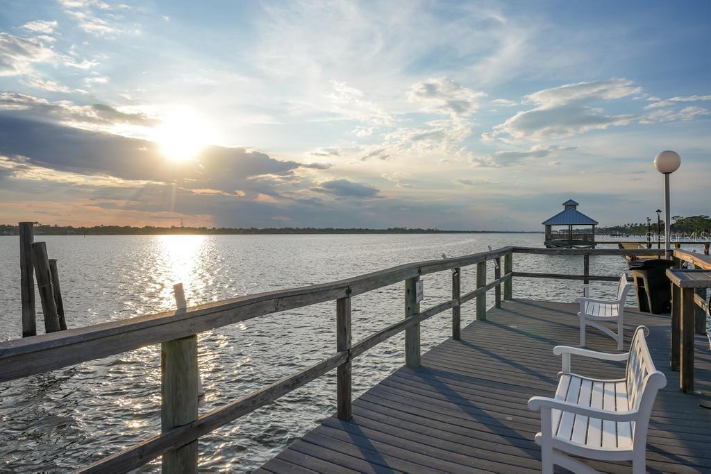 A wooden pier with white benches overlooks a calm body of water at sunset — 925 N HALIFAX AVENUE UNIT 410, DAYTONA BEACH, FL