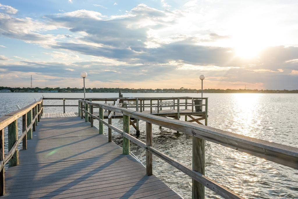 A wooden pier extends over a body of water toward a sunset horizon — 925 N HALIFAX AVENUE UNIT 410, DAYTONA BEACH, FL