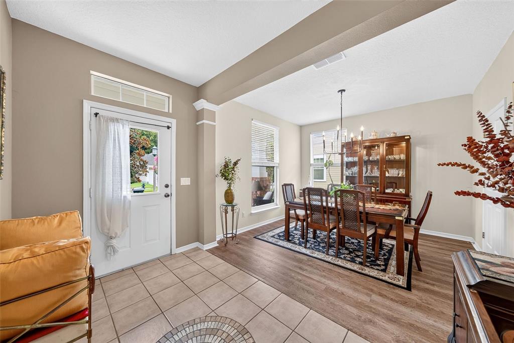A dining room with wood-look flooring and a tiled entryway features a wooden table set — 1103 BANKS ROSE COURT, CELEBRATION, FL