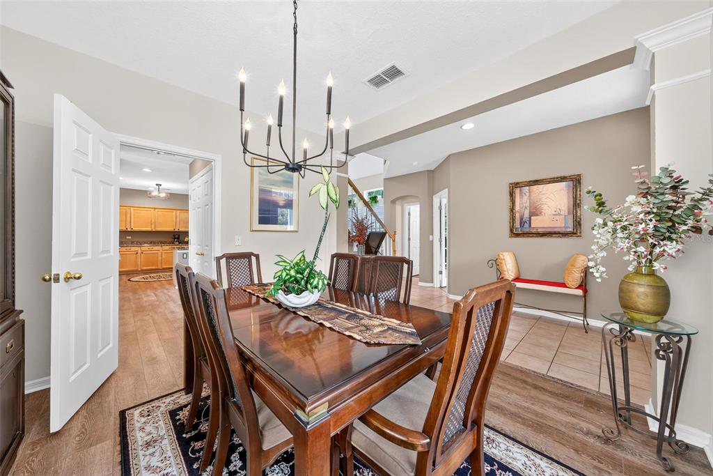 A dining room features a wooden table, a chandelier, and a view into the kitchen — 1103 BANKS ROSE COURT, CELEBRATION, FL