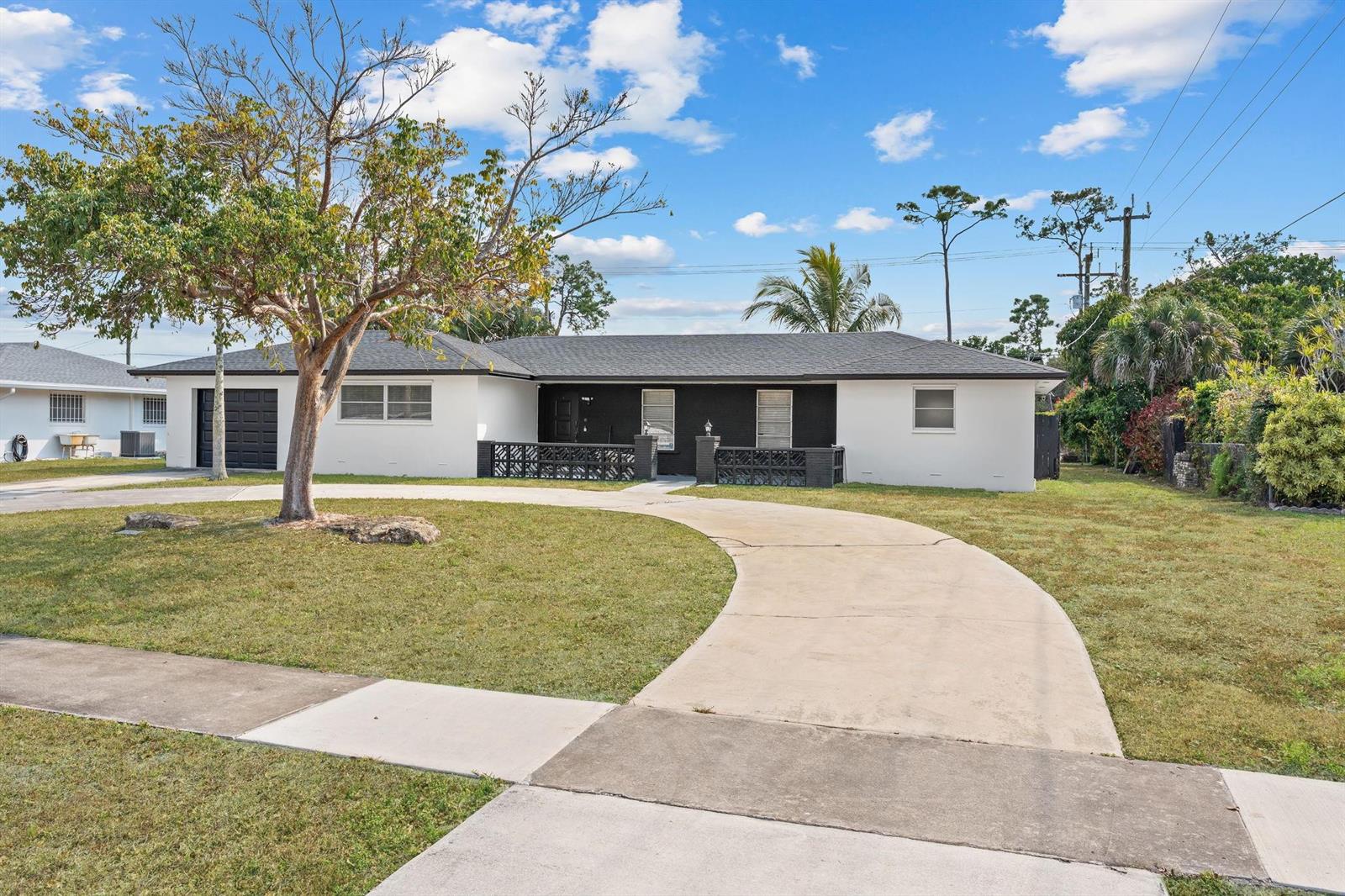 A single-story house with a white and black exterior features a curved concrete driveway — 7328 Saint Andrews Road, Lake Worth FL 33467, LAKE WORTH, FL