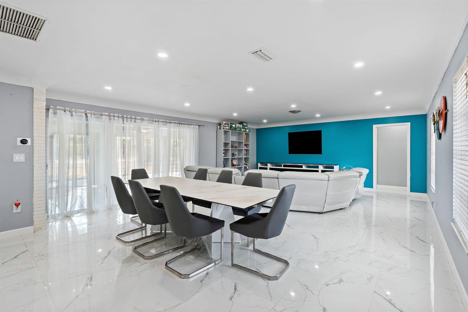 A dining area with a marble table and grey chairs sits before a blue-walled living room — 7328 Saint Andrews Road, Lake Worth FL 33467, LAKE WORTH, FL