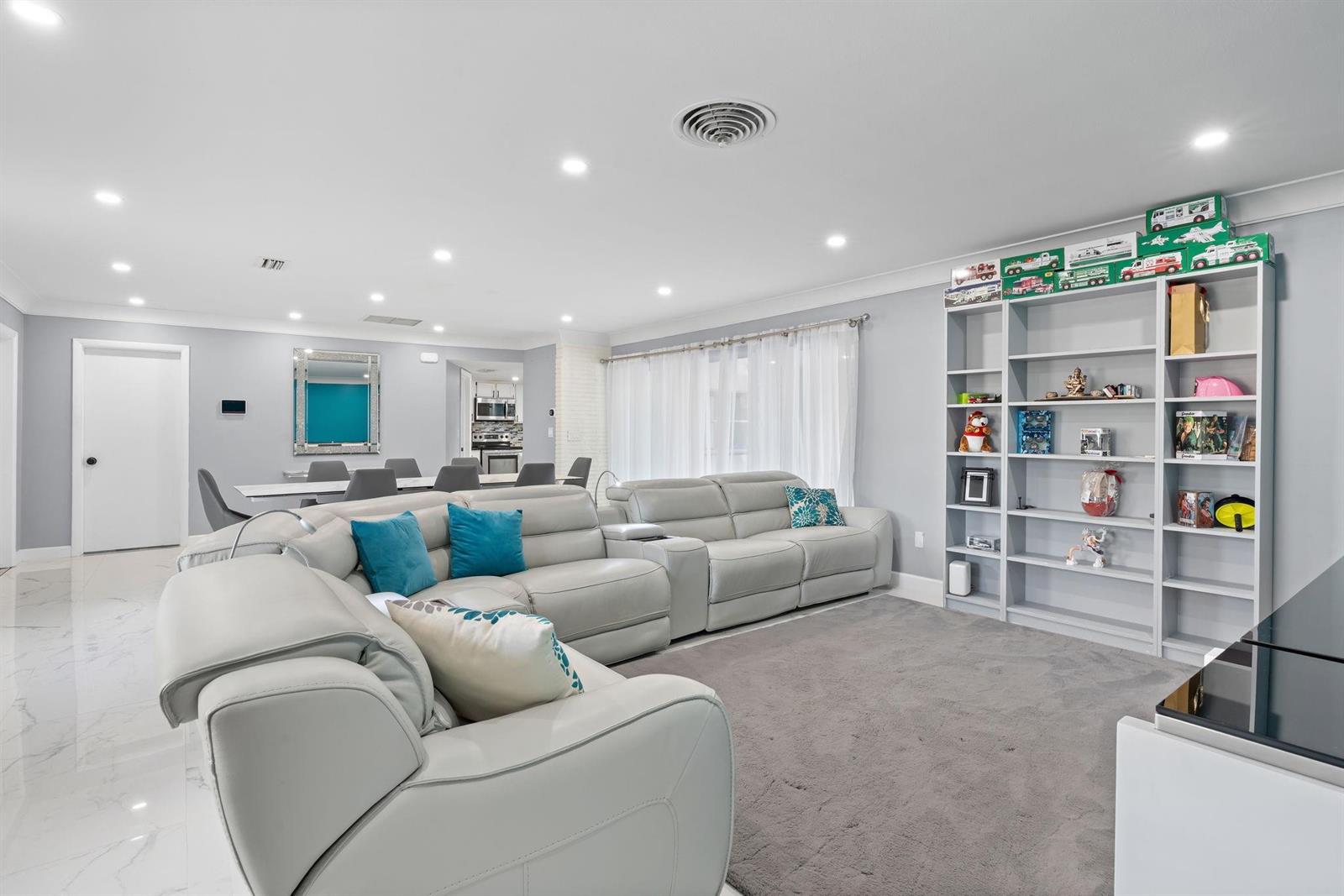 A living room with light gray walls, a sectional sofa, and a tall white bookshelf — 7328 Saint Andrews Road, Lake Worth FL 33467, LAKE WORTH, FL