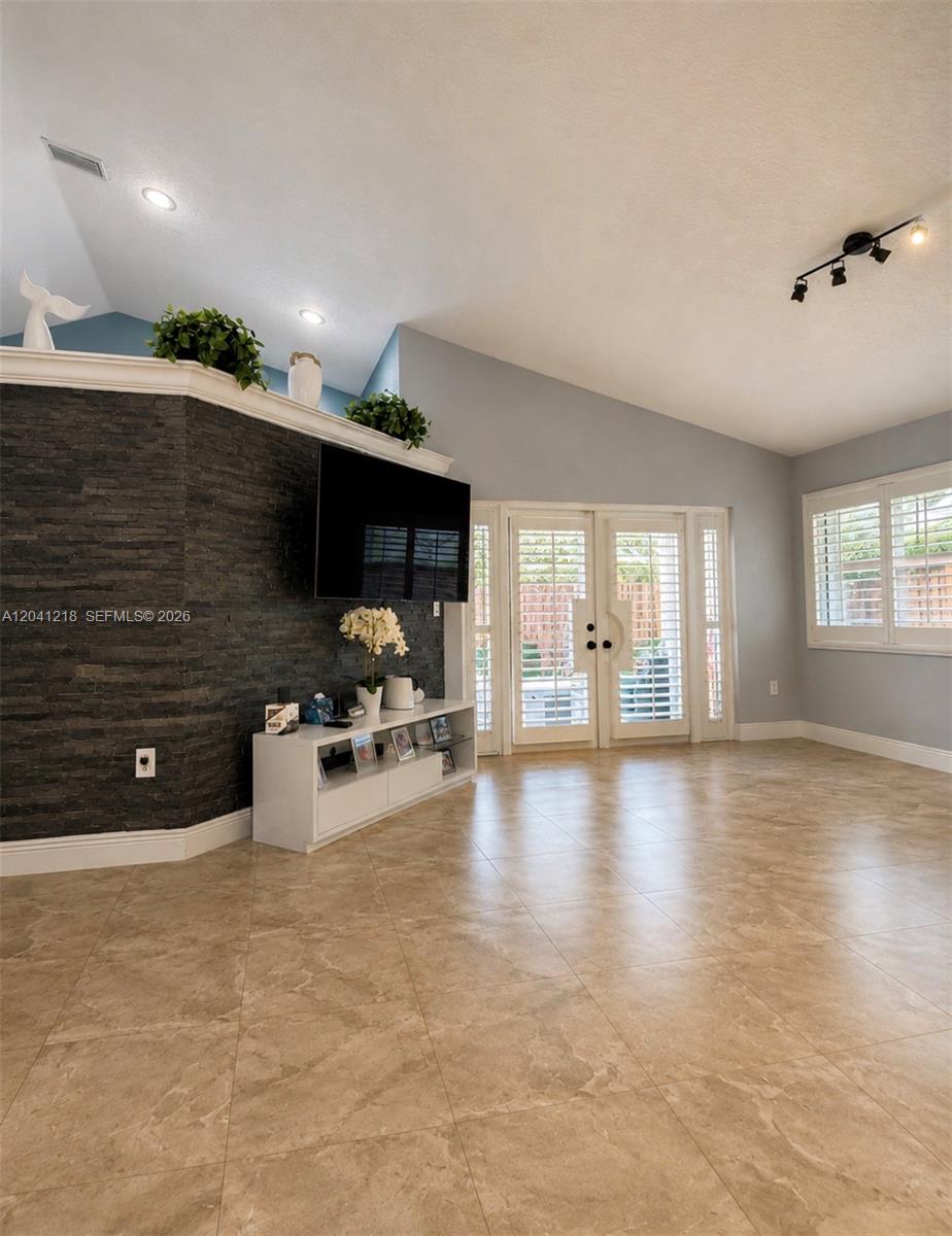 A living room features a dark stone accent wall, tile flooring, and glass patio doors — 12224 NW 30th Mnr, Sunrise FL 33323, SUNRISE, FL