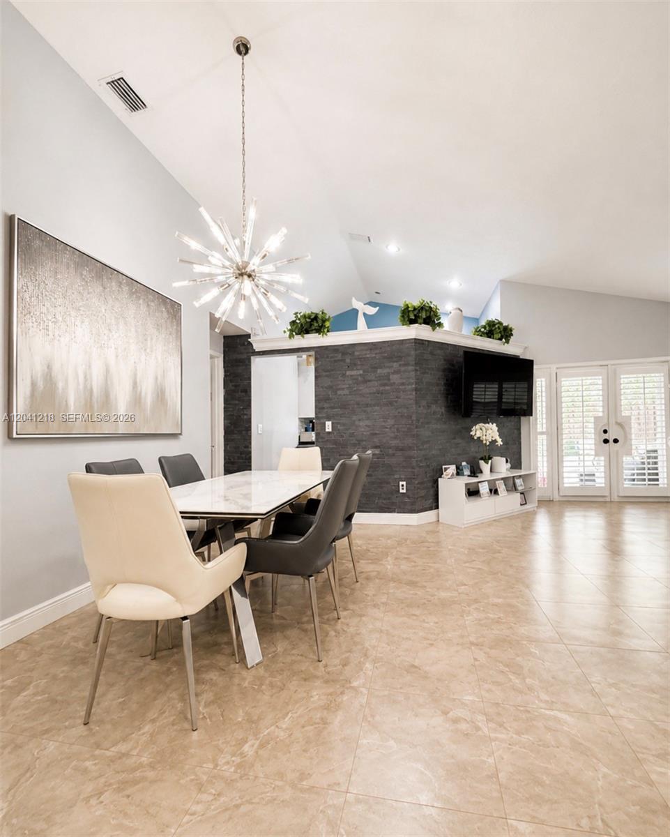A dining room features a marble-topped table, a starburst chandelier, and a dark stone accent wall — 12224 NW 30th Mnr, Sunrise FL 33323, SUNRISE, FL