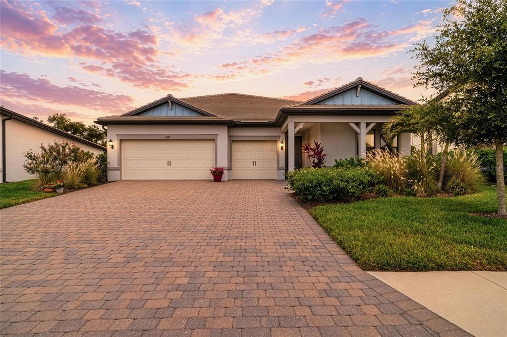 A single-story house with a paved driveway, two garage doors, and a covered front porch — 16341 HIDDEN OAK LOOP, LAKEWOOD RANCH, FL