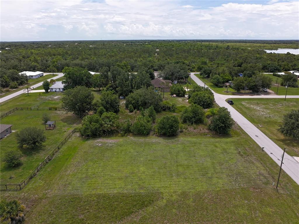 An aerial view shows a cleared, rectangular grass lot bordered by trees and a road — 31092 N BEND STREET, PUNTA GORDA, FL